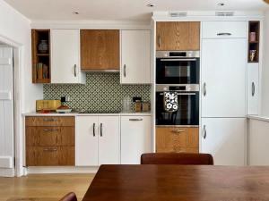 a kitchen with white cabinets and a wooden table at Mid-Century Gem - Heart of Frome in Frome