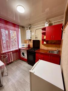 eine kleine Küche mit roten Schränken und einem Waschbecken in der Unterkunft 31 m City Center Apartment for 3 Near Central Market 1К у центрі, 31 м , біля Центрального ринку in Mykolajiw