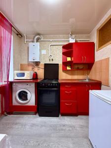 eine Küche mit roten Schränken und einer Waschmaschine in der Unterkunft 31 m City Center Apartment for 3 Near Central Market 1К у центрі, 31 м , біля Центрального ринку in Mykolajiw