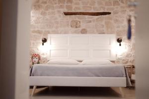 a white bed in a room with a stone wall at Pepenero Apulian Rooms in Noci