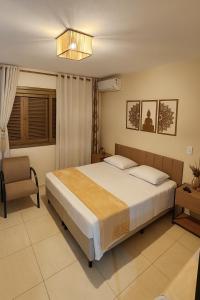 a bedroom with a large bed and a chair at LSViver Hospedagem in Caxias do Sul