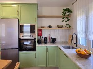 a green kitchen with green cabinets and a sink at Villa Rosa in Melgaço