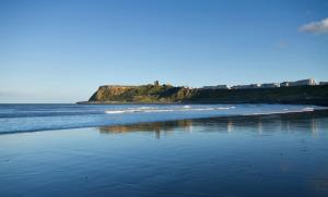 a beach with an island in the water at Columbus Holiday Flats in Scarborough