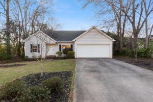 a white house with a garage on a driveway at The Clover Cottage in Normaltown in Athens