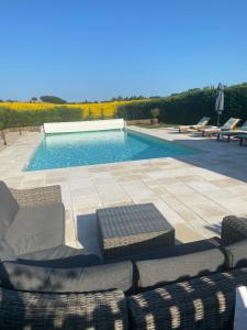 a pool with couches and chairs next to at Liguand Gites in Saint-Quentin-du-Dropt