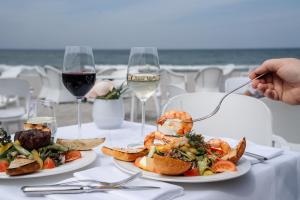 a table with two plates of food and glasses of wine at Strandhotel Fischland in Dierhagen