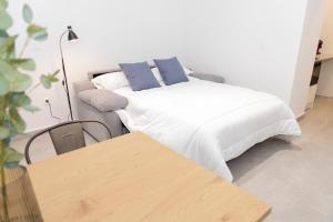 a bedroom with a white bed and a couch at UVA Apartamentos in Badajoz
