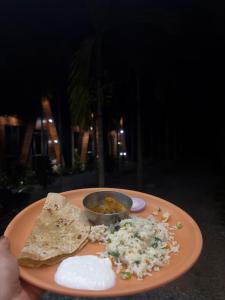 een persoon die een bord eten met een kom eten vasthoudt bij Raghavs Retreat Chikmaglur in Chikmagalūr