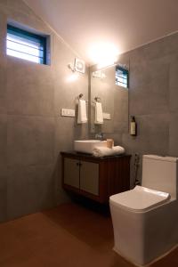 Un baño con inodoro, lavabo y espejo. en Notu by Raho - Secluded Villa with Estate View, en Siddapur