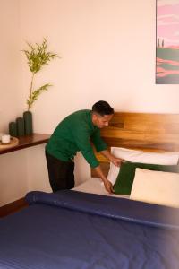 a man making a bed in a bedroom at Nila by Raho - Secluded Villa with Estate View in Siddapur