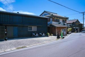 Eine Frau, die eine Straße entlang geht, neben einem Haus in der Unterkunft Ittokasi Ao no Ie - Vacation STAY 44156v in Fuefuki