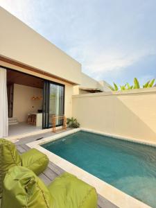 a swimming pool with chairs next to a house at Villa Saraswati I in Uluwatu