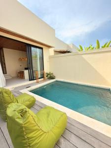 a swimming pool with chairs next to a house at Villa Saraswati I in Uluwatu