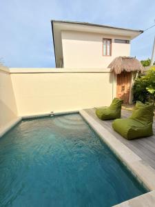 a swimming pool with green pillows in front of a house at Villa Saraswati I in Uluwatu