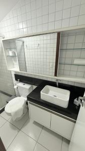 een badkamer met een wastafel, een toilet en een spiegel bij Muro Alto - Nannai Residence in Porto De Galinhas
