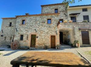 un antiguo edificio de piedra con una mesa de madera delante en Borgofortino, en Rovitolo 2 fotos más