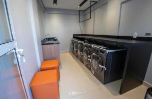 a laundry room with two washing machines and an orange stool at Apartamento Home Club, com dois quartos! in Foz do Iguaçu