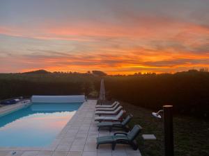 a swimming pool with lounge chairs and a sunset at Liguand Gites in Saint-Quentin-du-Dropt