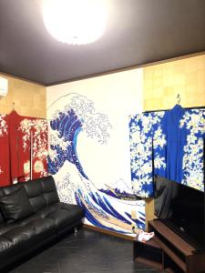 ein Wohnzimmer mit einer Wand, an der ein Gemälde eines Tsunamis hing in der Unterkunft ミラージュ宿 2025年5月オープン 京都芸術 1軒家貸切 in Kyoto