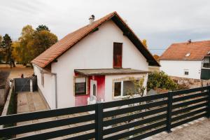 a white and red house with a black fence at Kuća za odmor Panonski mornar in Vukovar