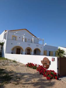 een wit huis met rode bloemen ervoor bij Ria Endless South - Barroca Village - Sítio da Fortaleza in Tavira