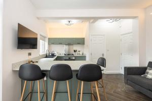 une cuisine avec un comptoir et quatre tabourets de bar dans l'établissement The Groves Room 3 First Floor, à Manchester