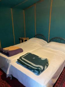 a bed with white sheets and green towels on it at Desert tours&trips in Zagora