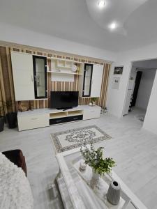 a white living room with a television and a table at La Monica - Straja - Lupeni - Retezat - Parang in Lupeni