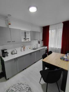 a kitchen with white cabinets and a wooden table at La Monica - Straja - Lupeni - Retezat - Parang in Lupeni