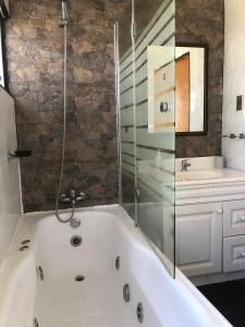a white bath tub with a shower and a sink at Casa de 5D para 12 personas con piscina in Guanaquero