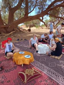 a group of people sitting on the ground under a tree at Desert tours&trips in Zagora