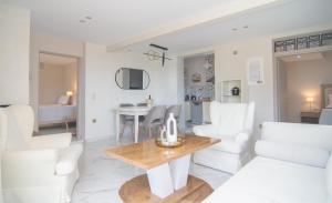 a living room with white chairs and a wooden table at Tango Sunset Villa in Paleokastritsa