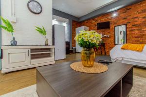 een woonkamer met een vaas met bloemen op een tafel bij Maboneng Black Diamond Oasis on Craftmanship Hotel with Wi-fi and Parking in Johannesburg