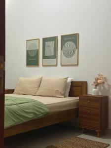a bedroom with a bed with three pictures on the wall at Kalakoala by Zzz in Malang