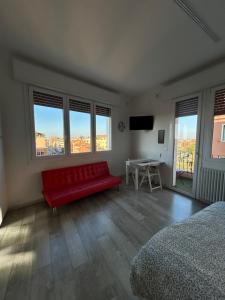 a bedroom with a red couch in a room with windows at Stayinbologna 3 in Bologna