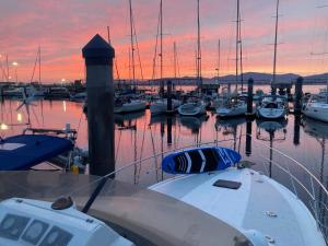 een groep boten aangemeerd in een jachthaven bij zonsondergang bij El yate de la Ría in Vigo +7 foto's