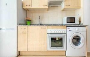 eine Küche mit Waschmaschine und Mikrowelle in der Unterkunft Apartamento con calefacción, balcón y hermosas vistas in Posada de Llanes