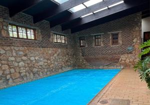 an indoor swimming pool with a stone wall and blue water at Millstream Farm Cottages in Dullstroom
