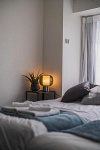 東京にあるERIKO HOTEL Azabujubanのベッドルーム1室(ベッド2台、ランプ、植物付)