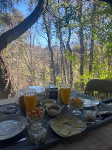 a picnic table with food and glasses of orange juice at Glamping, Piscina, Río y Bosque - Más Líderes Experiencias in Santiago
