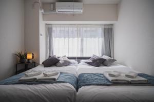 東京にあるERIKO HOTEL Azabujubanの窓のある部屋にツインベッドが2台