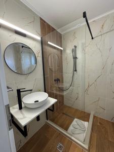 a bathroom with a sink and a shower with a mirror at Oana Boutique C D I in Bran