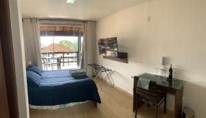 a bedroom with a bed and a desk and a window at Casa Indaiá in Petrópolis