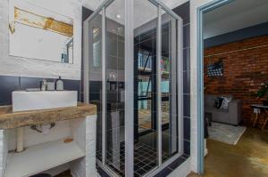 een badkamer met een wastafel en een spiegel bij Maboneng Black Diamond Oasis on Craftmanship Hotel with Wi-fi and Parking in Johannesburg +46 foto's