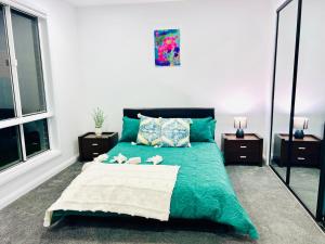 a bedroom with a green bed with two pillows at Modern 4 Bed 4 Bath Family friendly Villa in Melton South