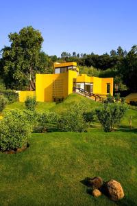 una casa amarilla en la parte superior de un frondoso patio verde en Hotel Casa en el Campo en Morelia