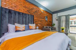 een slaapkamer met een groot bed met een bakstenen muur bij Maboneng Black Diamond Oasis on Craftmanship Hotel with Wi-fi and Parking in Johannesburg