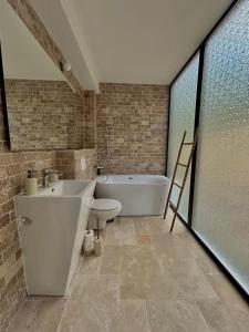 Un baño con bañera, inodoro y lavabo. en Zafra Chalet, en Poiana Ţapului