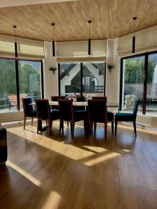 Un comedor con mesa y sillas y ventanas. en Zafra Chalet, en Poiana Ţapului