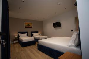 una habitación de hotel con dos camas y una silla en Villa Klaus Center Hotel, en Tirana